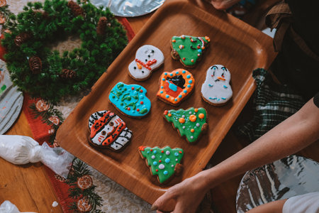 An overhead view of a wooden board displaying Christmas gingerbread cookies baked by children during...