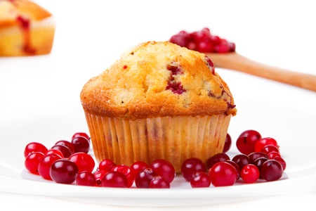 Cake on a plate with cranberries. Wooden spoon with cranberries in the backgroundの写真素材