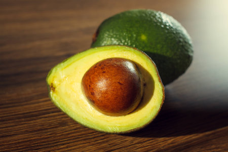 Ripe avocado on a wooden background.Whole and half fruit