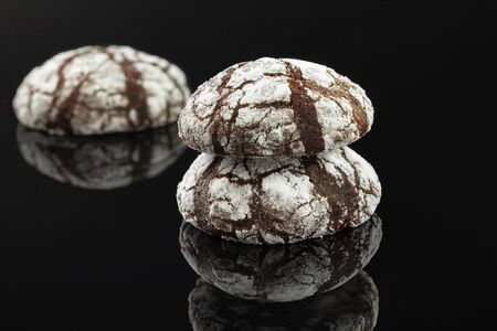 Home made chocolate chip cookies with cracks. Covered with white powdered sugar. On a black background.の写真素材