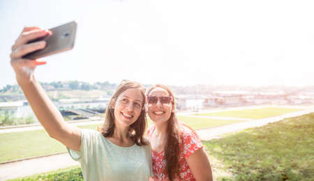 Girlfriends taking selfie together having fun outdoors