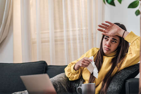 Young adult girl woman sick staying at home got flu red and runny nose having fever and high...