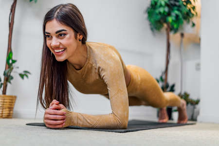 Fit, active and attractive young female girl woman stretching before or after exercise at home...