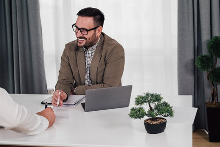 Smiling businessman discussing business plan with male partner. Entrepreneurs are planning strategy...
