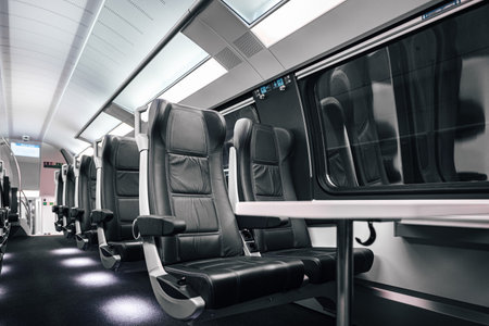 Empty table and comfortable leather seats by window. Interior of modern illuminated passenger train....