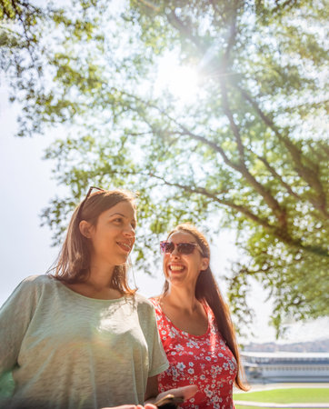 Girlfriends walking together having fun outdoors concept of modern women friendship lifestyle female best friends happy girls travel on break or city vacation bright warm day laughing cheerfulの写真素材
