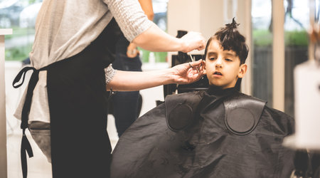 Hairdressers hands making hairstyle to child little boy in the barber shop hair cut professional - Little boy in the barber shop hair cut professional toddler child getting his first haircut curiousの写真素材