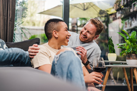 Young adult persons couple enjoying themselves and having great time at home casual atmosphere drinking wine smiling laughing happy feelings joy relaxedの写真素材