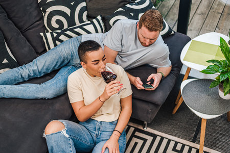 Happy two persons couple shopping online young people purchasing web shop, entrepreneur pays using portable devices, couple enjoying buying gifts sitting on floor with laptop and smartphone at home.の写真素材