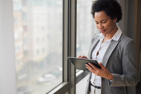 Stylish adult woman in a suit, checking her mail box on her tablet, while at work.の写真素材