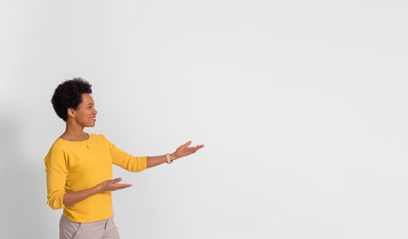 Young businesswoman presenting new product over copy space while standing on white backgroundの写真素材