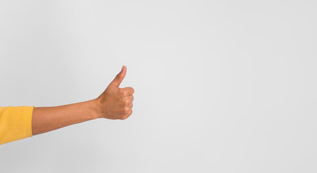 Cropped hand of positive businesswoman showing thumbs up sign against white backgroundの写真素材