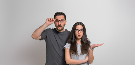 Portrait of worried and scared young couple dressed in casuals looking at camera shockingly. Amazed...