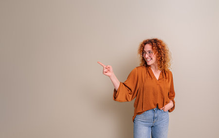 Smiling businesswoman with hand in pocket aiming at copy space for advertisement isolated on...