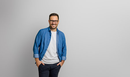 Confident young businessman with hands in pockets smiling and standing isolated on white backgroundの写真素材