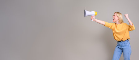 Furious female activist gesturing and screaming over megaphone while standing on white backgroundの写真素材