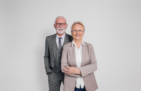 Confident mature businessman and businesswoman in glasses smiling and standing on white backgroundの写真素材