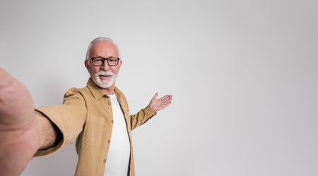 Portrait of confident senior businessman in glasses presenting new product over white background