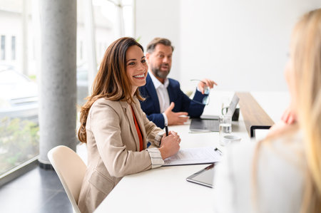 Confident businesswoman and businessman with documents and laptop discussing business plans in...