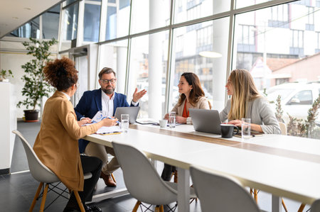 Businessman explaining project details over laptop to female coworkers in conference room during...