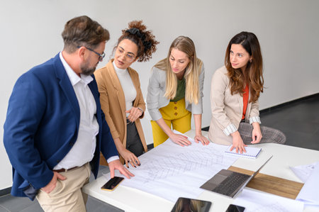 Male and female architects with blueprint on table discussing and planning new project in modern officeの写真素材