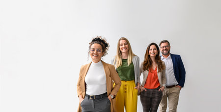 Portrait of confident business people with hands in pockets smiling and standing in a row over white...