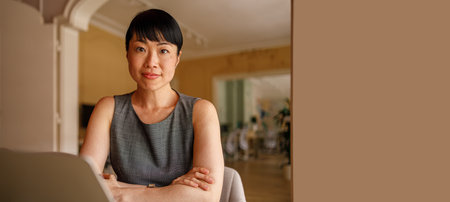 Confident businesswoman looking at camera while working over computer at desk in corporate workplace
