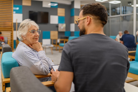 Senior woman listening attentively to male ophthalmologist during routine eye checkup at hospital clinicの写真素材