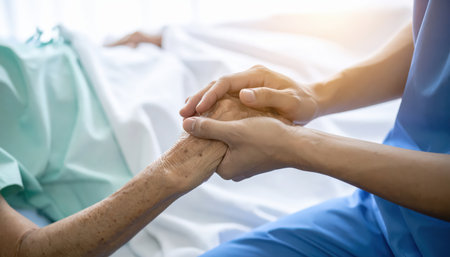 Hand of doctor holding hand of senior patient on bed in hospital.の素材