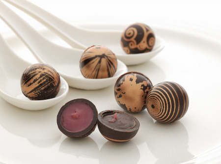 Chocolates filled with praline, served on white china spoons and plateの写真素材
