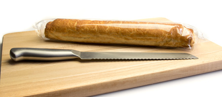 Wrapped almond bar with knife on a wooden plate isolated on a white backgroundの写真素材