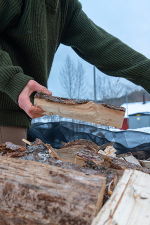 Stacking Firewood Outdoors in Snowy Countryside.