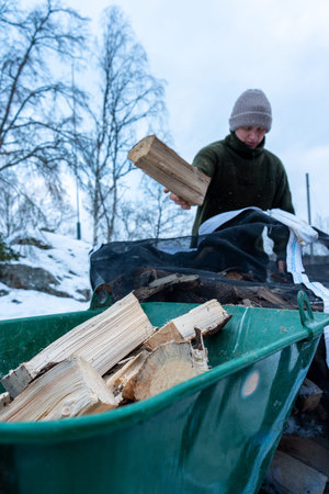 Stacking Firewood Outdoors in Snowy Countryside.の写真素材