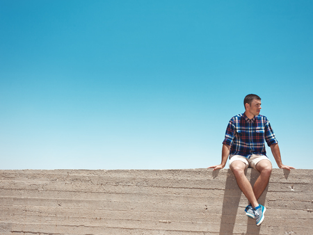 Man sitting on cement wall at sunny dayの写真素材