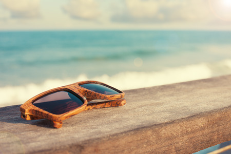 wooden sunglasses lying near the sea on woodの写真素材