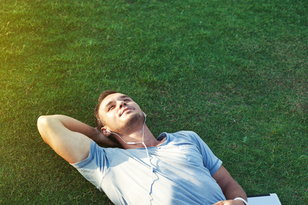 young man on the grass listening music on tabletの写真素材