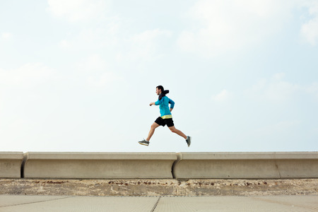 athletic sportsman running over concrete border near the oceanの写真素材