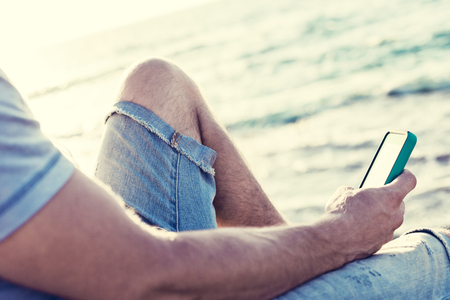 mobile smartphone in man's hands near the seaの写真素材