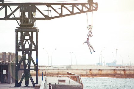 brave man hanging on the crane above the waterの写真素材