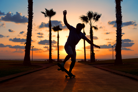 man riding on skateboard near the ocean in sunsetの写真素材