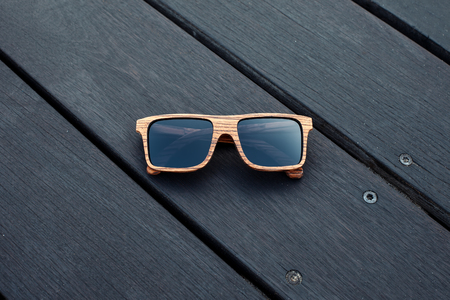 wooden sunglasses lying on the dark wet floorの写真素材