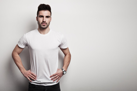 Serious man in white blank t-shirt, white wall background