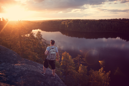 Brave traveler man with backpack looking at sunset near the river outdoorsの写真素材