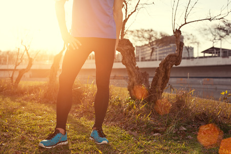 Young athlete standing in park at sunset (intentional sun glare)の写真素材