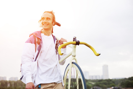 smiling man in blank t-shirt with bicycle in green field (intentional sun glare and bright color)の写真素材