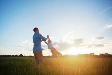 father spinning with his son in the park at sunset (intentional sun glare)の写真素材