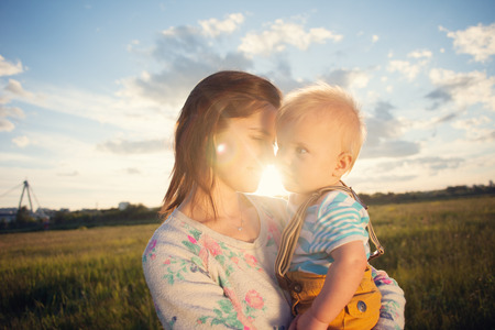 Happy mother and her baby spending time in the park outdoors (intentional sun glare)の写真素材