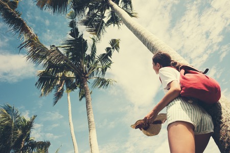 Young and happy girl standing near palm tree at resort on holidays intentional vintage colorの写真素材