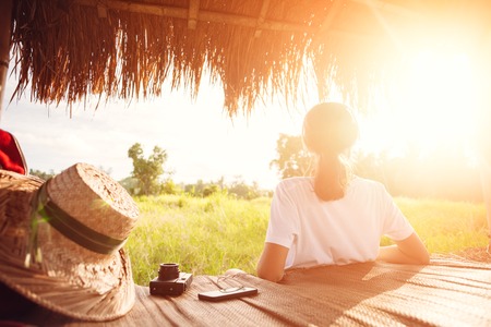 Young girl sitting and relaxing outdoors and listening music with headphones at good sunny day intentional sun glareの写真素材