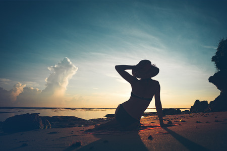 Silhouette of woman in hat resting on the beachの写真素材